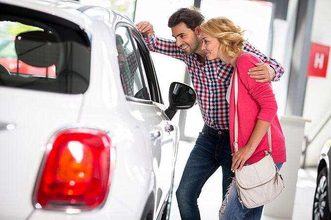 Young  couple chooses to buy a car in car dealership saloon